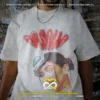 Fotografía de playera oversize blanca unisex con estampado de letras tipo graffiti rojo con el nombre Rosalía y retrato urbano con visera de la artista